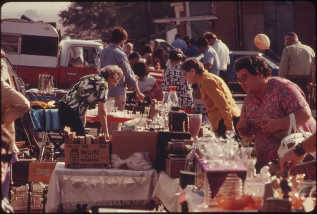 Shoppers browsing tables at a vintage outdoor flea market, the original way resellers found deals